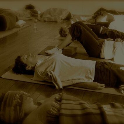 Yogis in Savasana in a yoga studio to depict the peaceful end to a Yoga class.